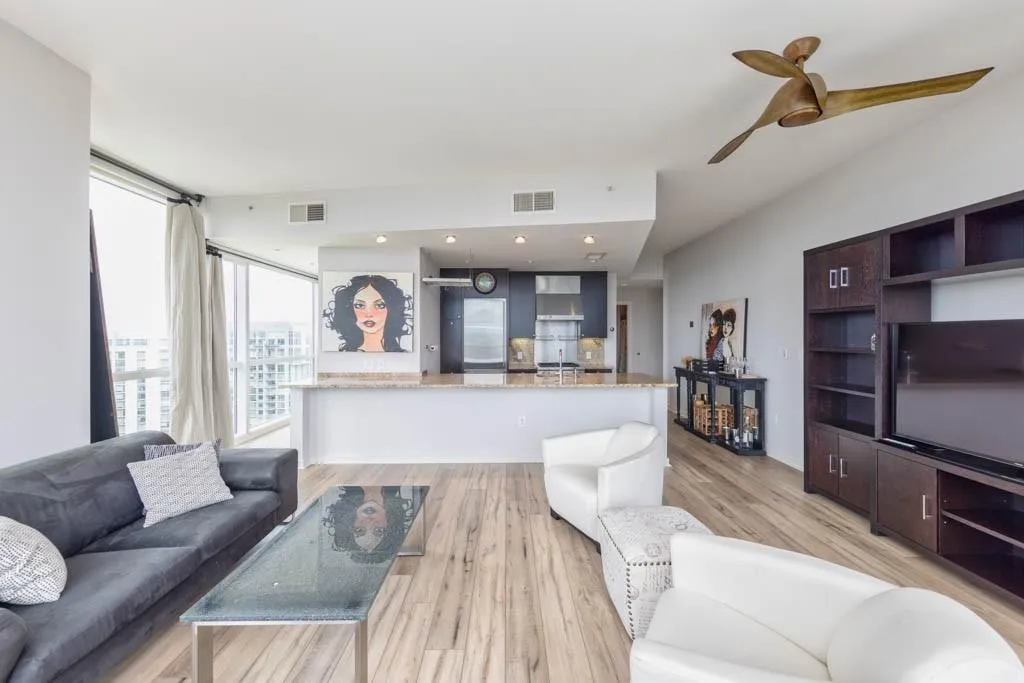 Living area with light wood-type flooring, ceiling fan, and a wall of windows
