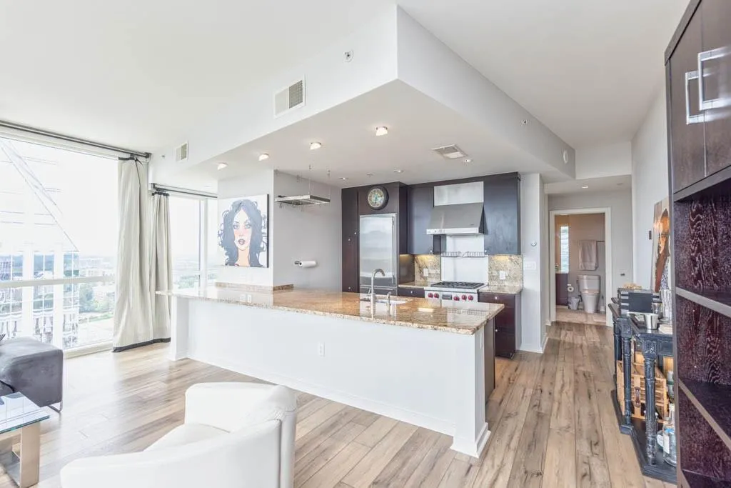 Kitchen with light wood finished floors, floor to ceiling windows, light stone countertops, and high quality fridge