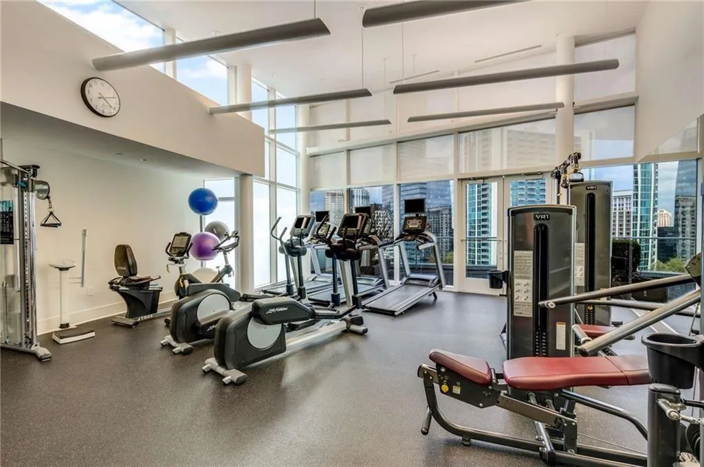 Exercise room featuring a towering ceiling, floor to ceiling windows, and a view of city