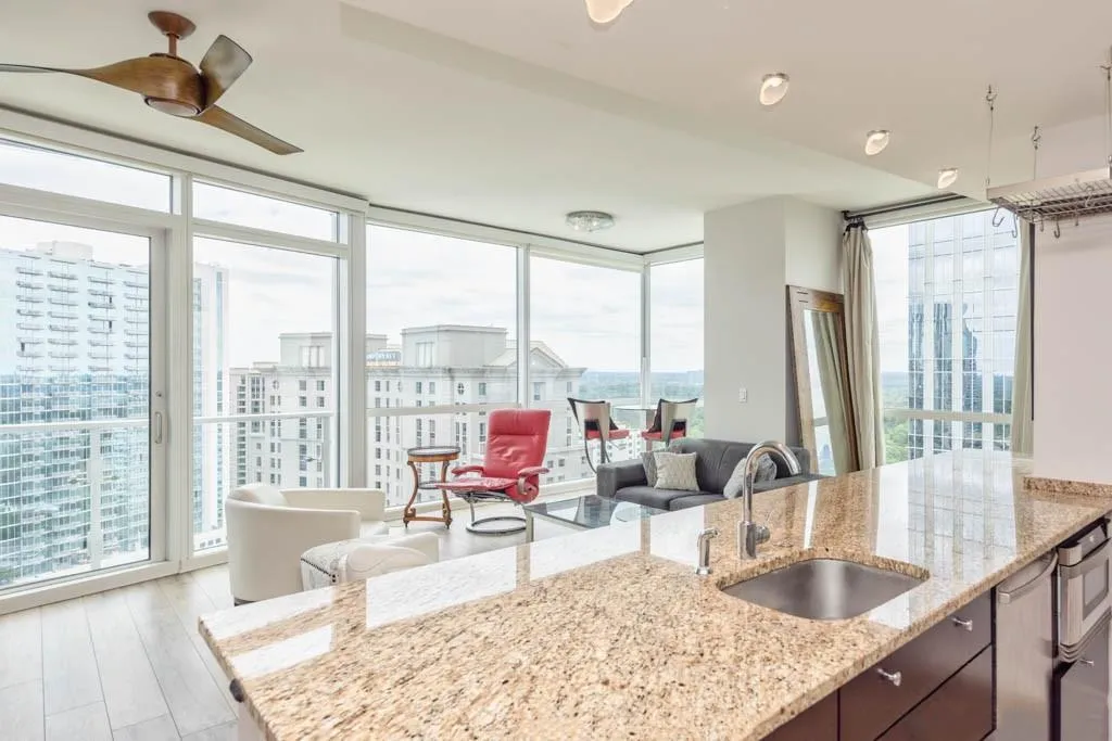 Kitchen featuring floor to ceiling windows, plenty of natural light, light stone countertops, a city view, and a peninsula