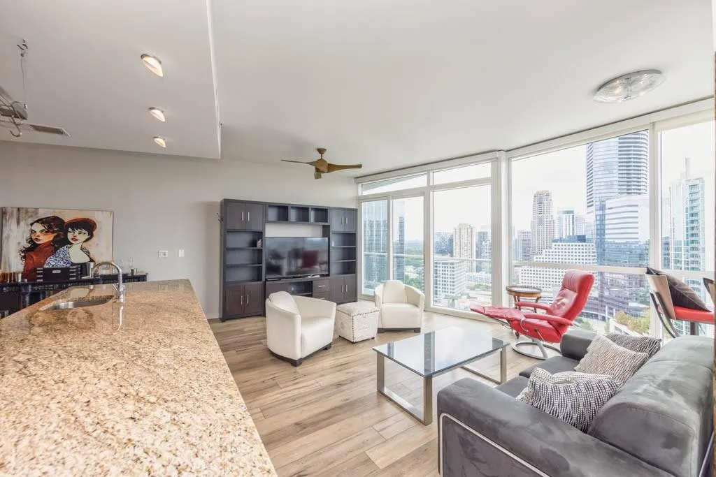 Living area with a wall of windows, light wood finished floors, and a ceiling fan