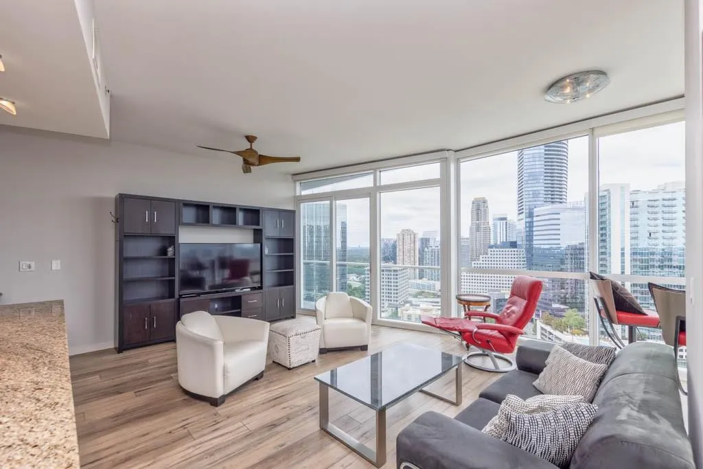 Living room featuring floor to ceiling windows, light wood-style flooring, and a ceiling fan