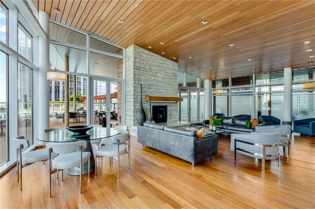 Living room featuring expansive windows, wood ceiling, light wood-type flooring, a fireplace, and a towering ceiling