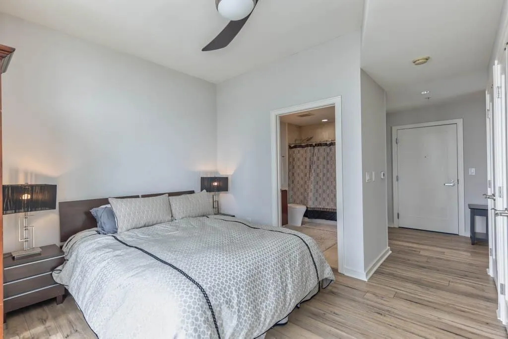 Bedroom featuring light wood-type flooring, ensuite bath, and ceiling fan