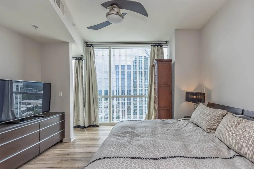 Bedroom featuring expansive windows, light wood finished floors, and ceiling fan