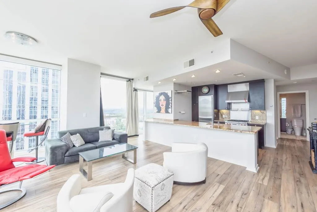 Living room featuring ceiling fan, light wood-style floors, and floor to ceiling windows