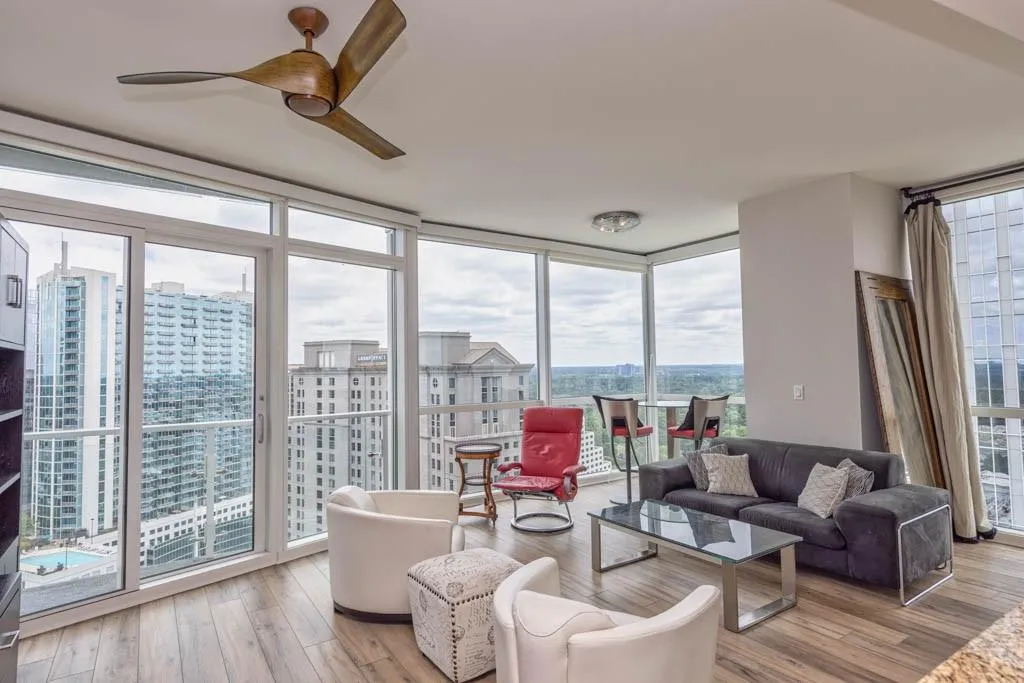 Living area with floor to ceiling windows, a city view, light wood-style flooring, and a ceiling fan
