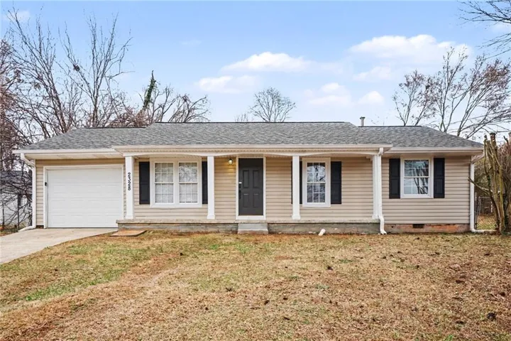 Ranch-style home featuring covered porch, a shingled roof, an attached garage, driveway, and a front yard