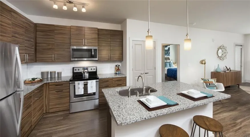 Kitchen with dark hardwood / wood-style flooring, sink, hanging light fixtures, and stainless steel appliances