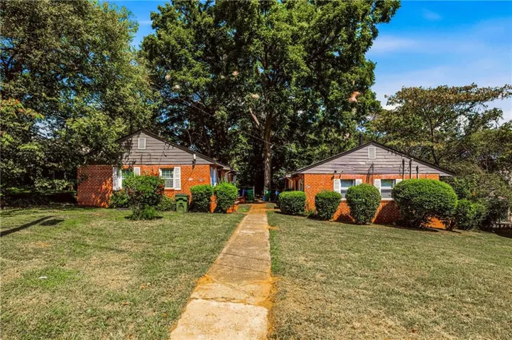 Two brick residences with gabled roofs, mature trees, and a concrete pathway
