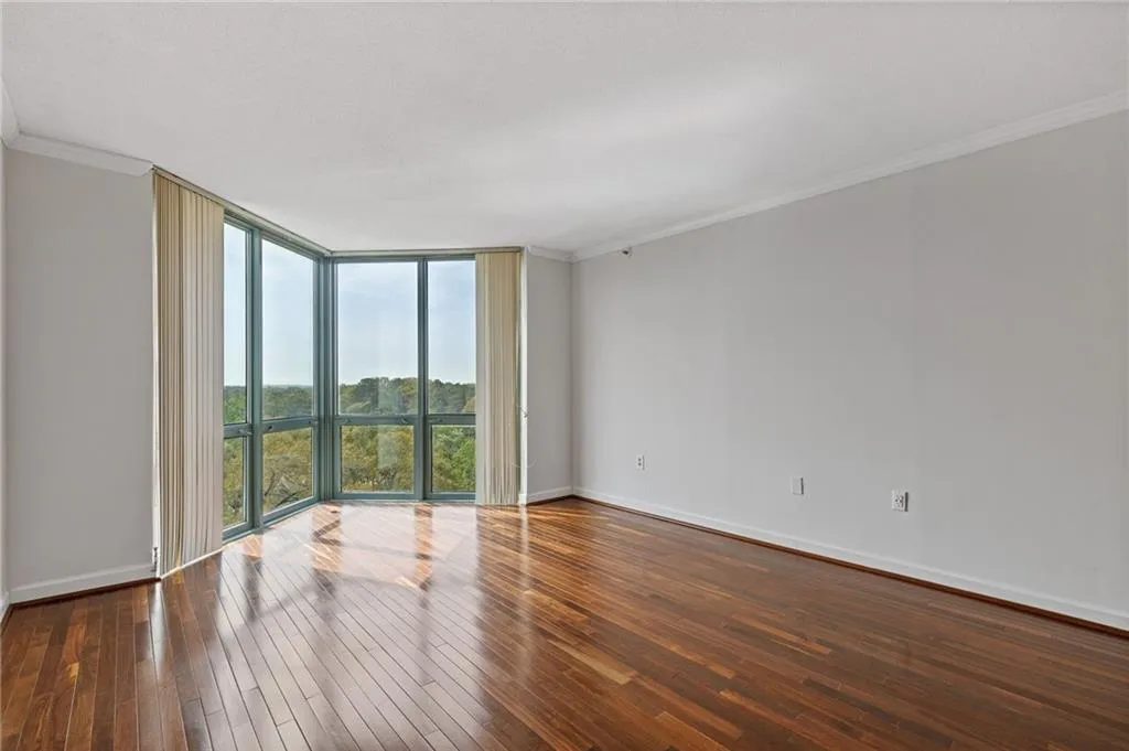 Spare room featuring expansive windows, crown molding, and dark wood-type flooring