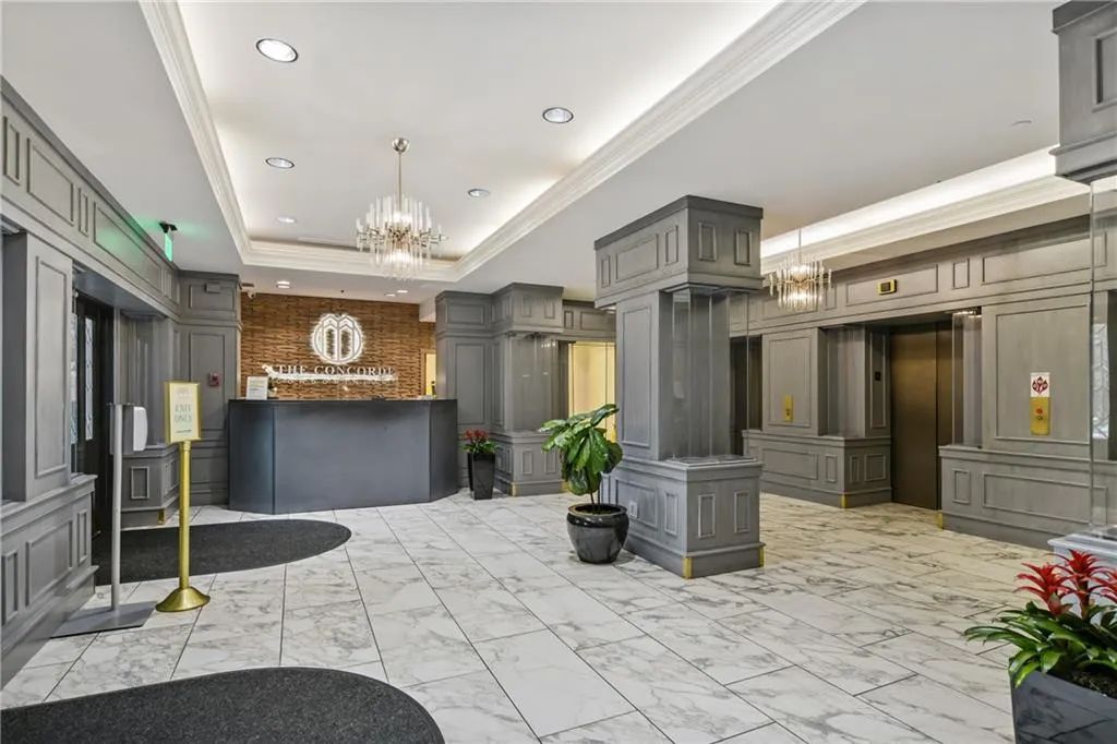 Welcome area with hanging lights, crown molding, a decorative wall, and a tray ceiling