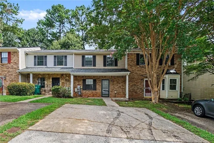 Townhome exterior featuring a combination of brick and siding, a covered entry, and black window shutters