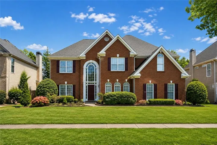Brick exterior with dark shutters, arched entry window, and a gabled roofline