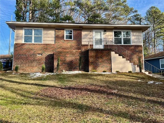 Brick and siding exterior with concrete steps and metal railings