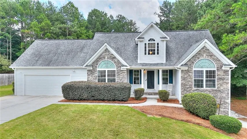 Stone and siding exterior with arched windows, prominent dormer, and attached garage