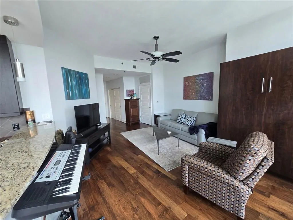 Living room featuring dark wood-style flooring and a ceiling fan