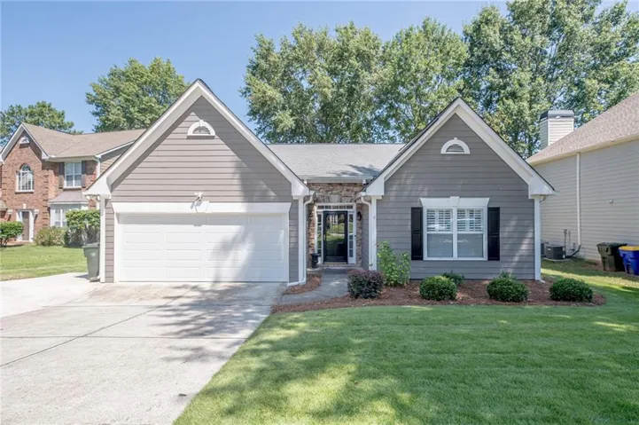 Gray siding exterior with stone accents, a two-car garage, and a concrete driveway
