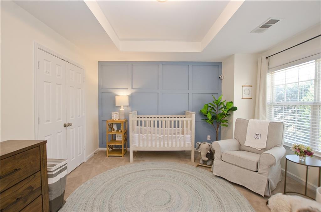 Bedroom with a nursery area, a raised ceiling, and a closet Bedroom with a nursery area, a raised ceiling, and a closet