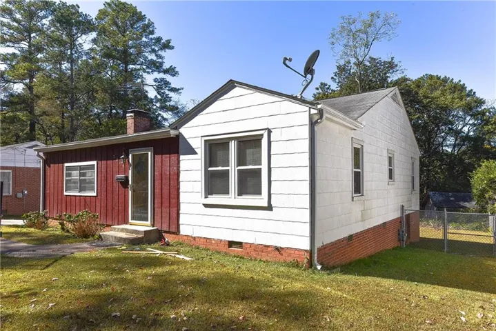 Exterior featuring white horizontal siding and red vertical siding, a brick foundation, multiple windows, and a chimney