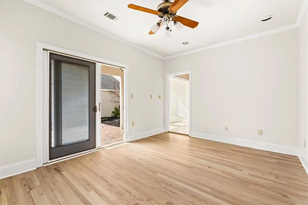 Empty room with ceiling fan, crown molding, and light wood-style floors