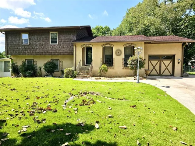 View of front of property featuring stucco siding, a garage, concrete driveway, and a front yard