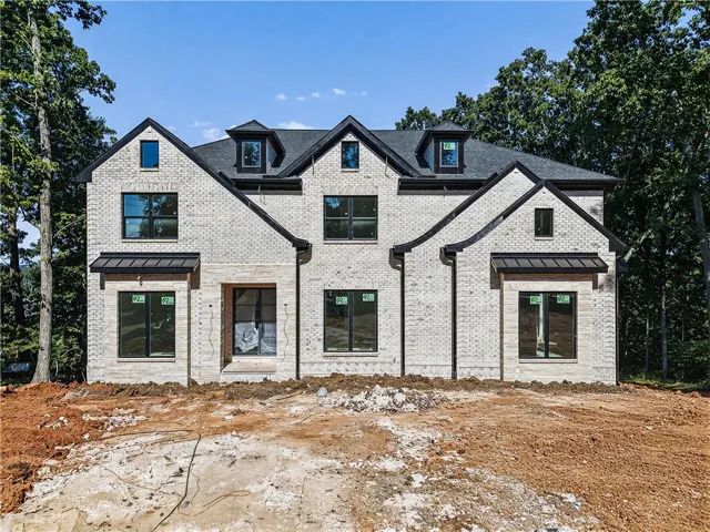 Light-colored brick exterior with a dark shingle roof, multiple gables, and dark-framed windows