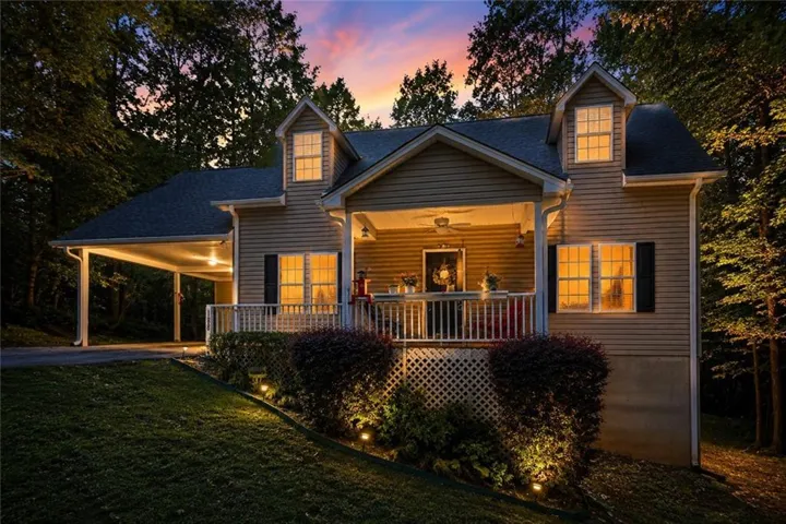 Siding exterior with dormer windows, covered front porch, carport, and landscape lighting