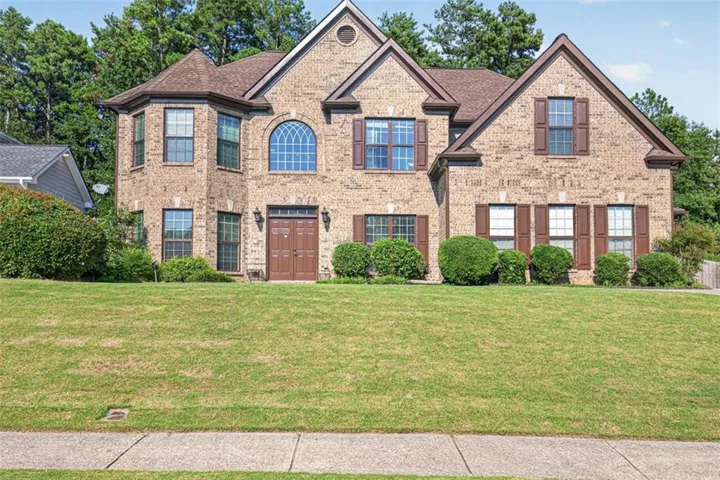 Brick facade residence featuring a prominent bay window, arched window above the entry, and multiple gabled rooflines