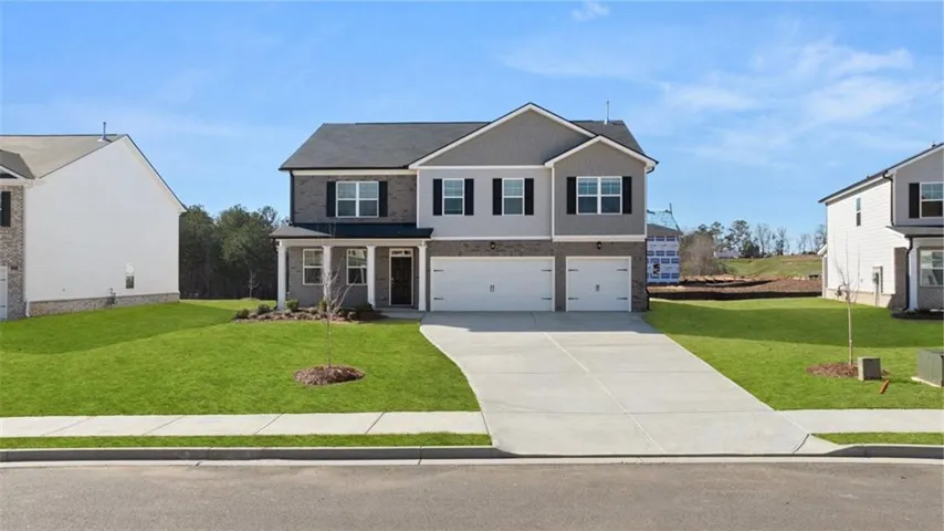 View of front facade featuring a garage, a front yard, driveway, and brick siding