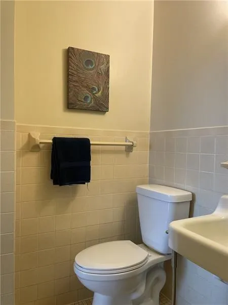 Bathroom featuring tile flooring, toilet, and tile walls