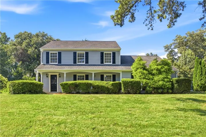 Classic Colonial-style residence featuring a two-story facade with symmetrical windows, white trim detailing, and a charcoal-gray asphalt roof