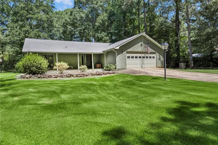 Expansive lawn, two-car garage, established landscaping, paved driveway, and mature trees