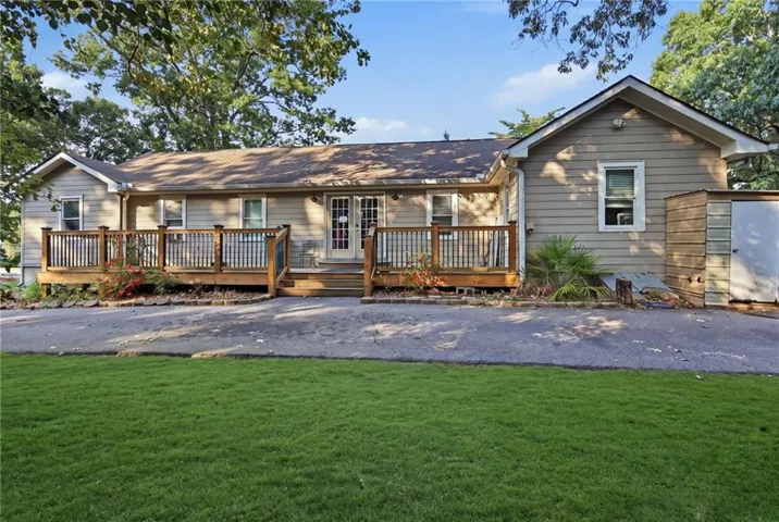 Rear exterior featuring a wood-plank deck with railing, dual glass-paneled doors, and a detached storage shed