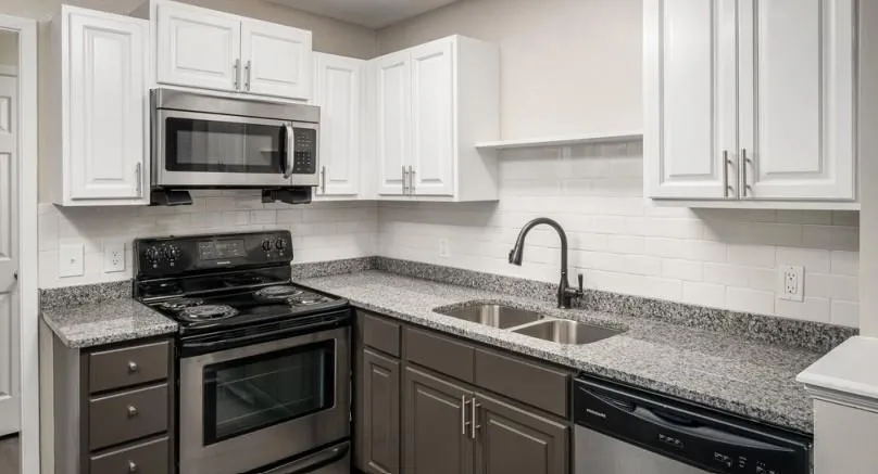 Kitchen with stainless steel appliances, white cabinetry, light stone counters, tasteful backsplash, and gray cabinetry