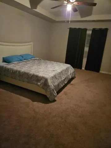 Tray ceiling with recessed lighting, ceiling fan, and wall-to-wall carpeting