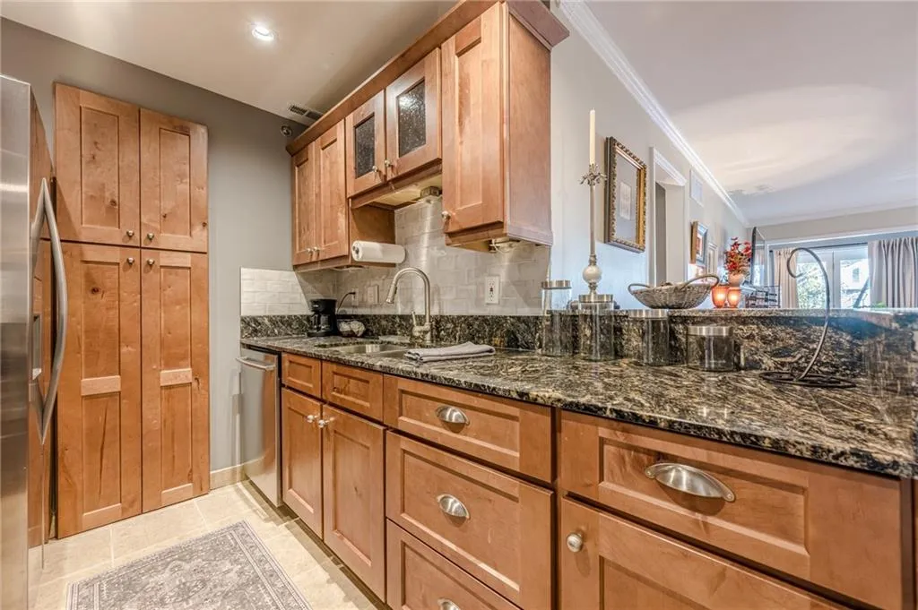 Kitchen featuring stainless steel appliances, ornamental molding, tasteful backsplash, brown cabinets, and dark stone countertops
