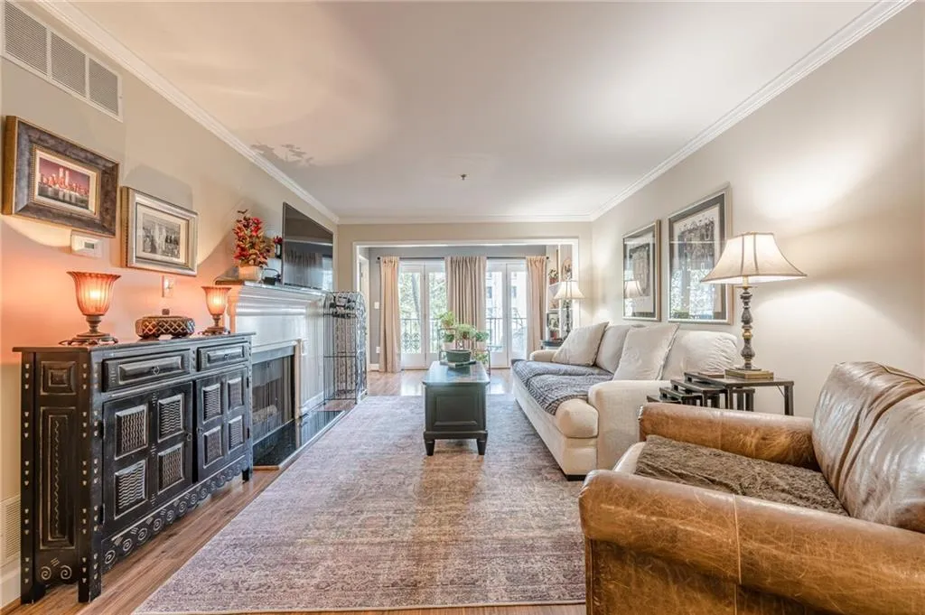 Living area featuring wood finished floors, crown molding, and a fireplace