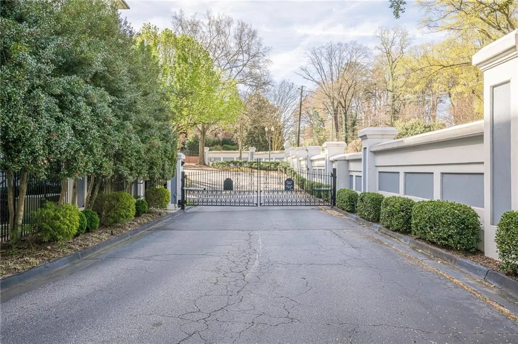 View of asphalt road featuring a gate, curbs, and a gated entry