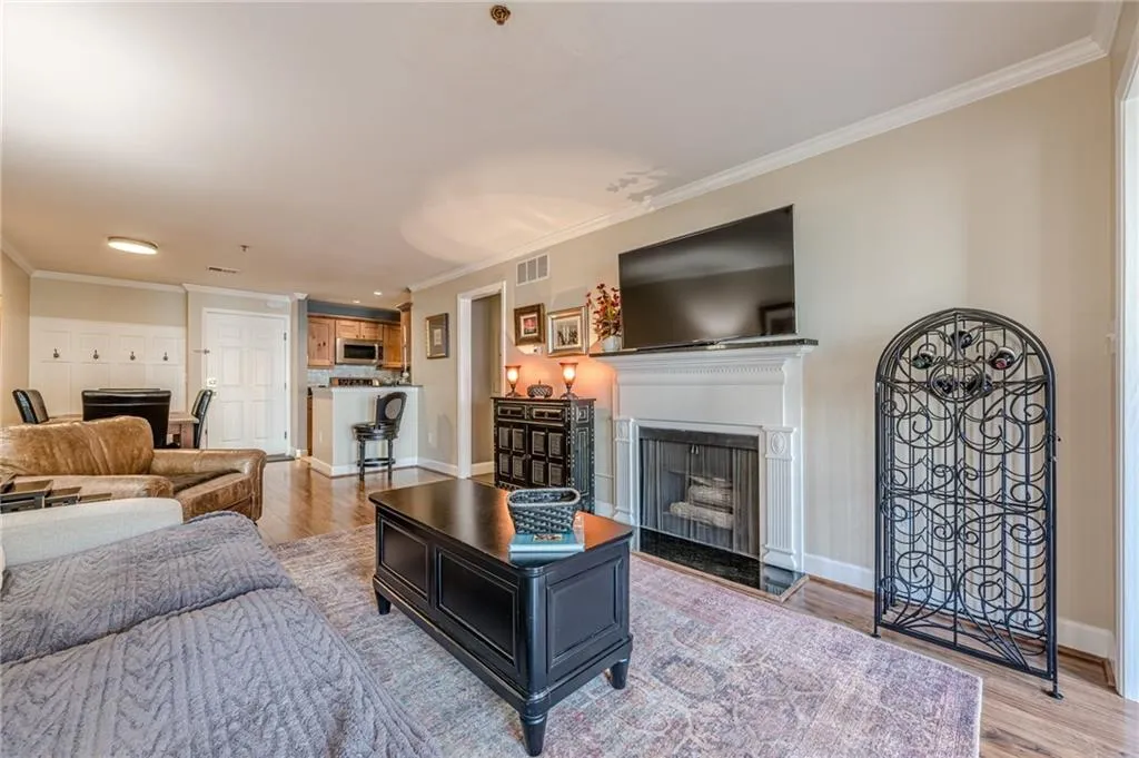 Living room with crown molding, light wood finished floors, and a fireplace with flush hearth