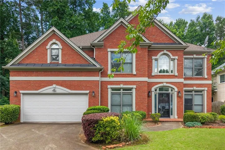 Two-story brick exterior featuring a multi-gabled roofline and a two-car garage