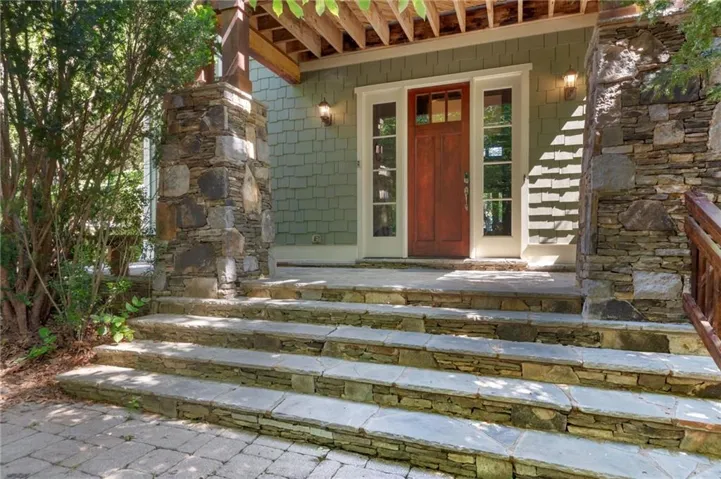 Stone-clad entry stairs leading to a solid wood front door with sidelight windows