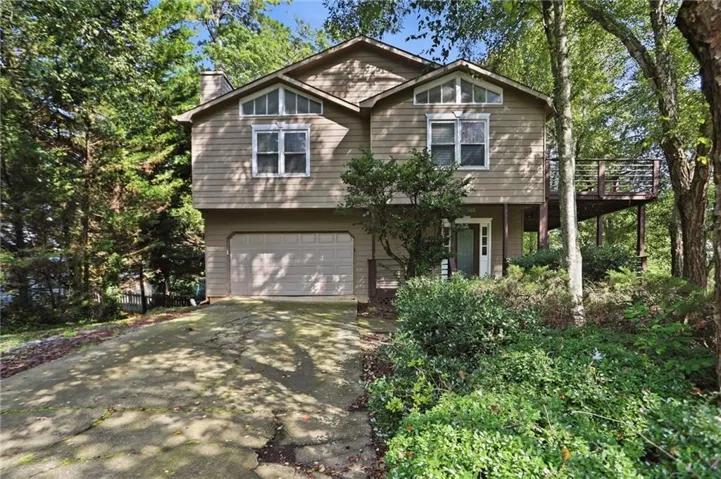 Multi-level residence featuring a two-car garage, an upper-level deck, and a front entry door with sidelights