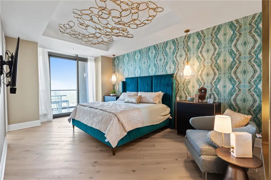 Bedroom featuring a tray ceiling, hardwood / wood-style floors, wallpapered walls, and expansive windows