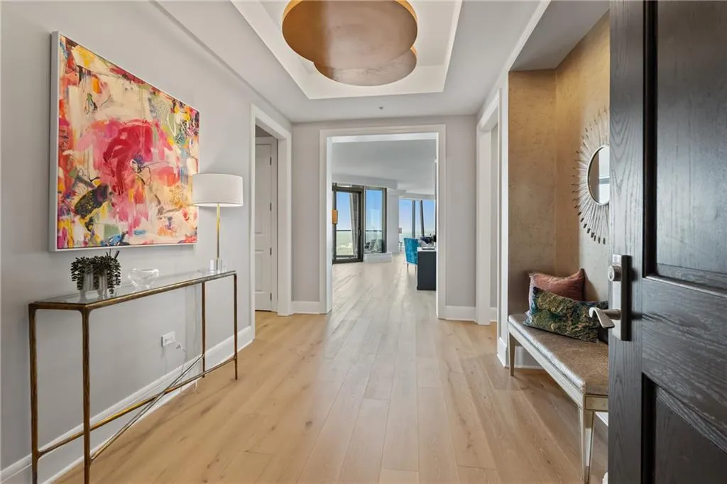 Corridor featuring light wood-style flooring and a tray ceiling