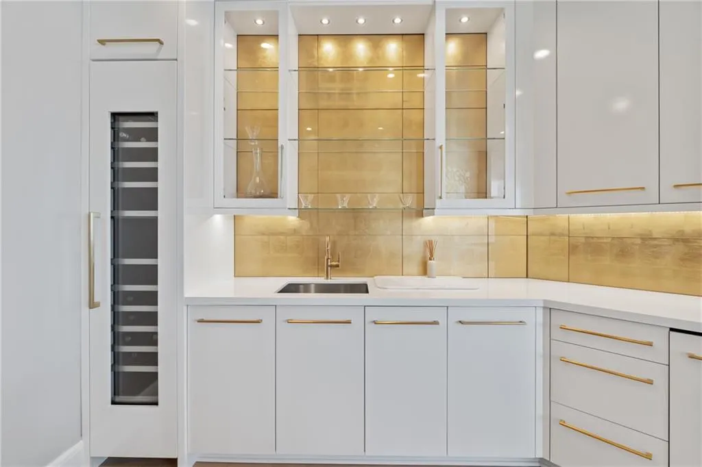 Bar area featuring white cabinetry, backsplash, glass insert cabinets, modern cabinets, and light stone countertops