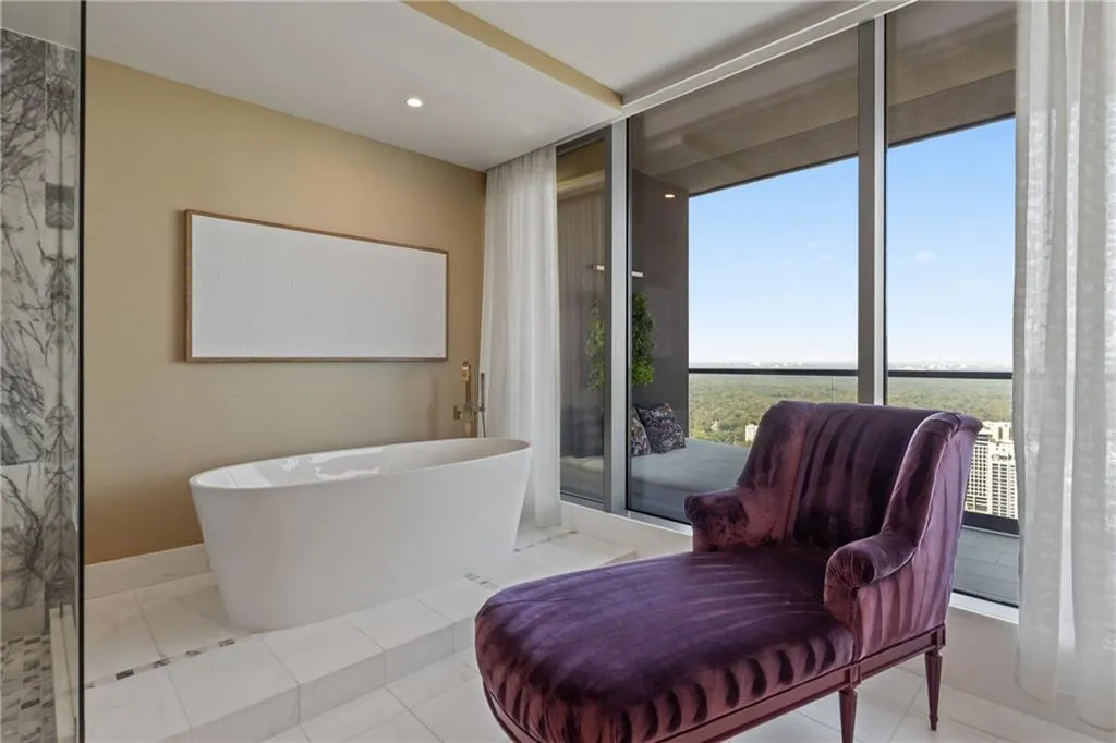 Bathroom with a freestanding tub, tile patterned flooring, a wall of windows, and recessed lighting