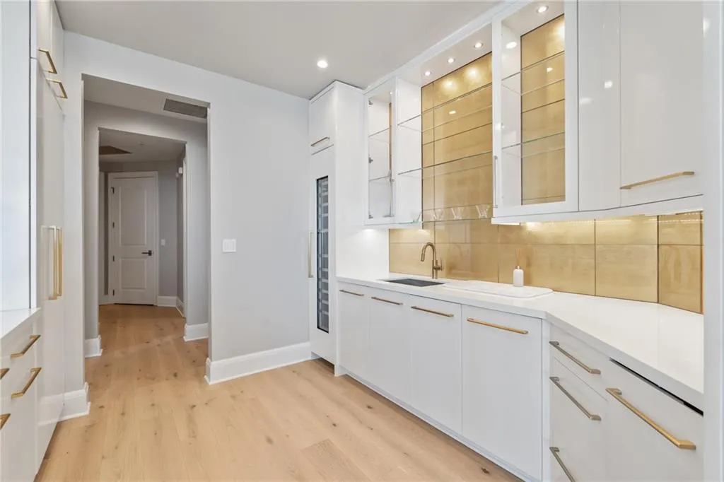 Kitchen with white cabinets, modern cabinets, glass insert cabinets, light wood finished floors, and tasteful backsplash