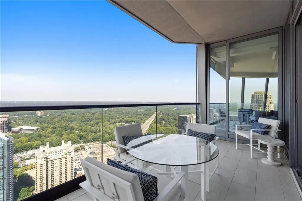 Balcony with a view of trees, outdoor dining space, and a view of city