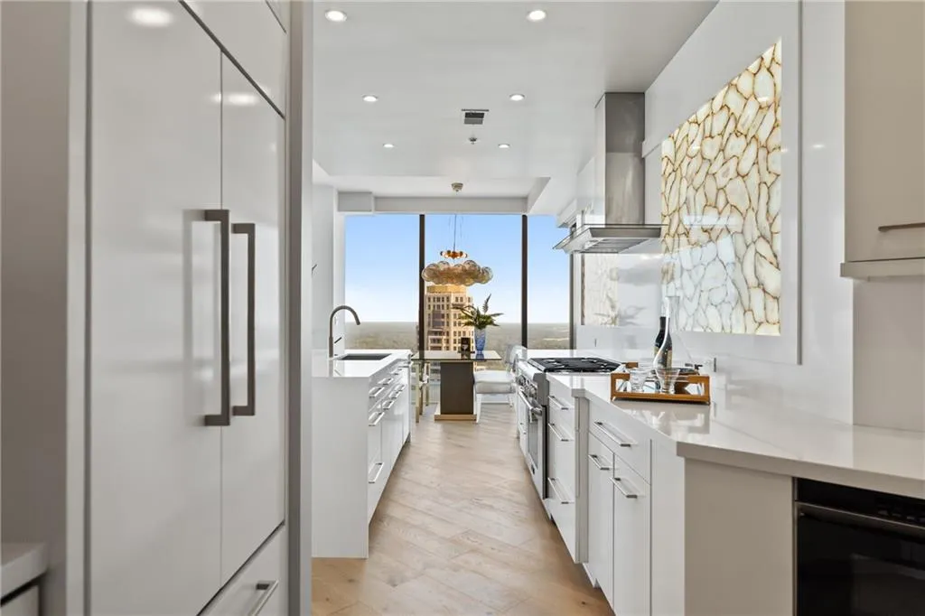 Kitchen featuring high end appliances, pendant lighting, light wood finished floors, white cabinets, and recessed lighting
